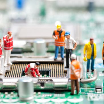 Miniature workers inspecting a computer motherboard closely.