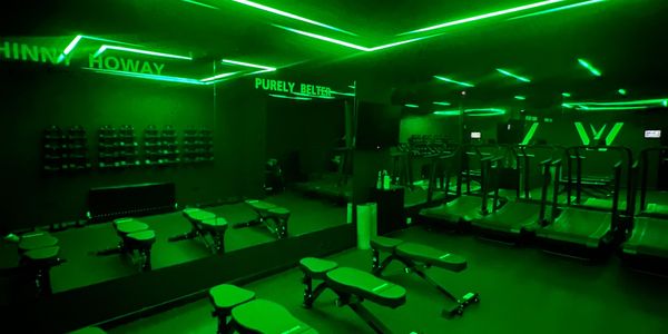 A gym with green neon lighting and workout equipment.