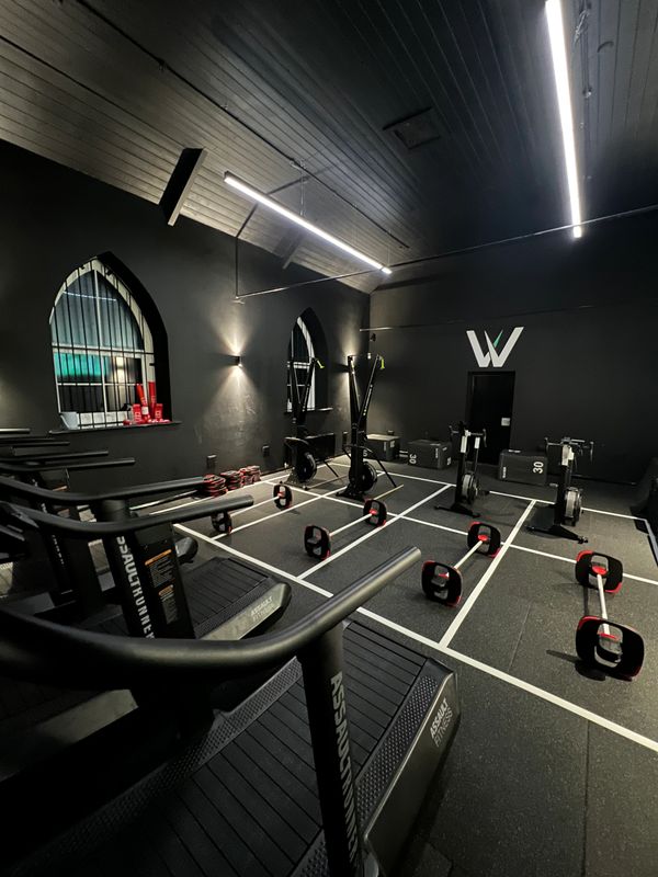 Modern gym with treadmills, rowers, and weight bars in a sleek black interior.