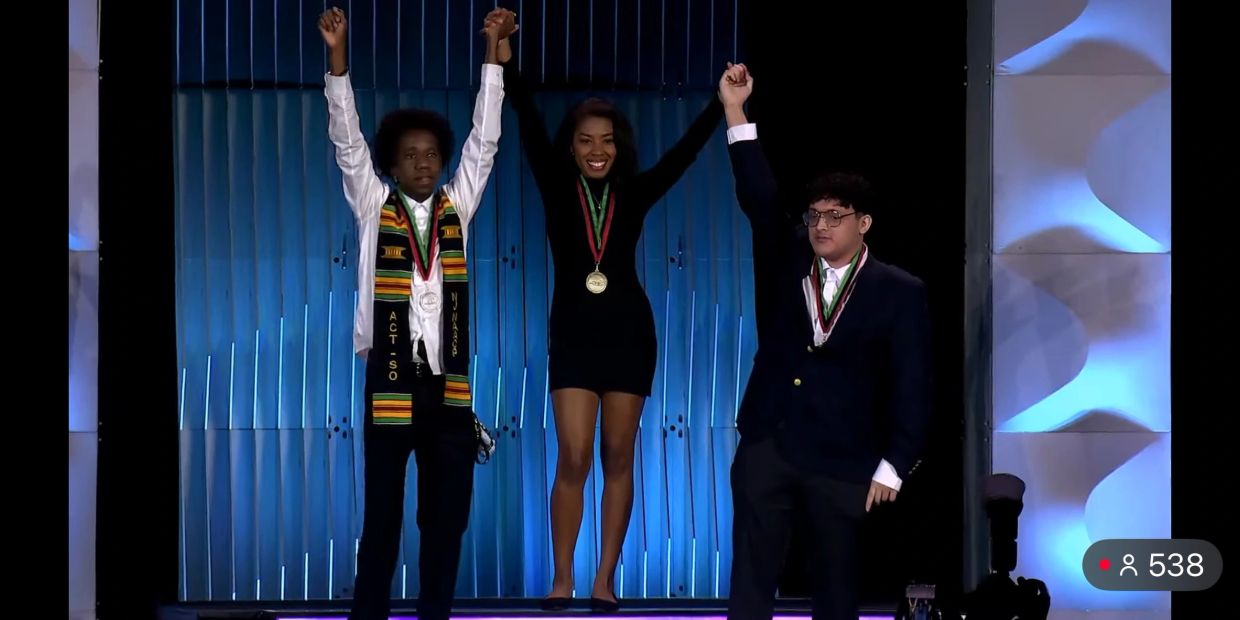 Three young winners celebrating with raised hands and medals.