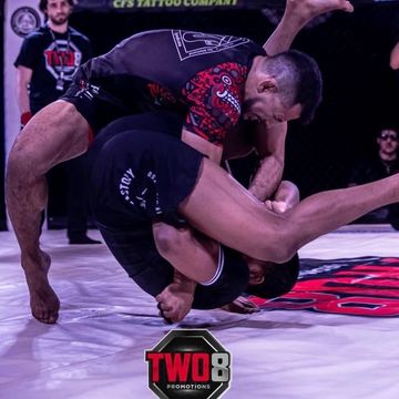 Two fighters engaged in an intense grappling match on the mat.