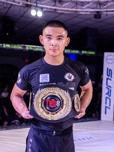 MMA fighter proudly holding championship belt inside cage.