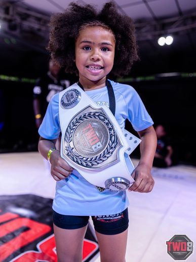 Young girl proudly holding a championship belt.