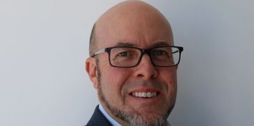 Man with glasses smiling at the camera.