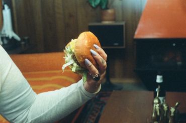 Person holding a sandwich with a wooden interior background.