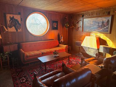 Cozy vintage living room with warm wood paneling and natural light.