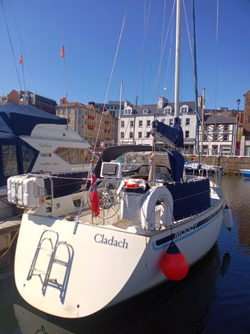 Sailboat named Cladach docked at a marina on a sunny day.