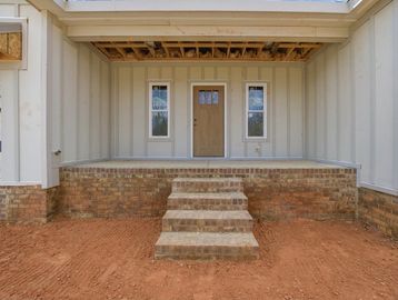 Unfinished porch with brick steps and a door under construction.
