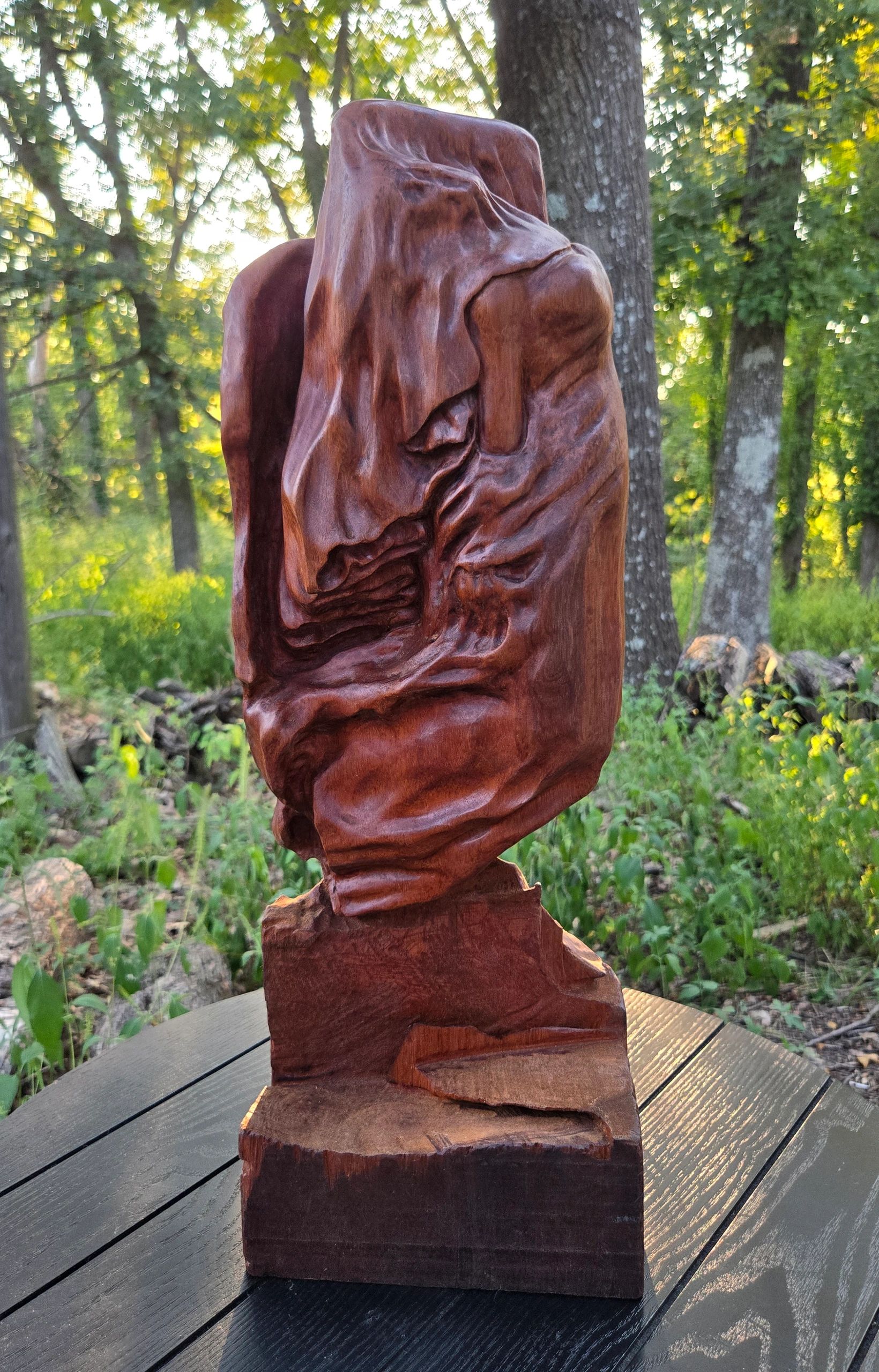 A veiled woman ascending as she removes her face covering carved in Brazilian Mahogany by Chad Rev