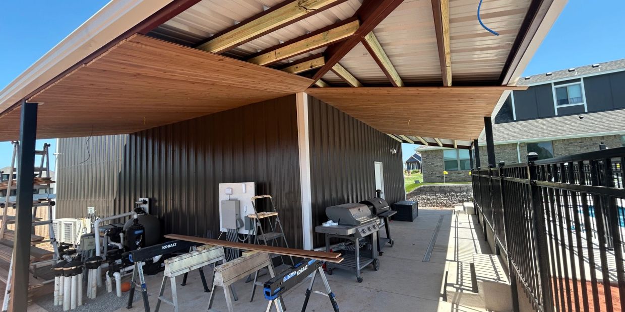 Modern outdoor workspace with tools and grills under a corrugated metal roof.