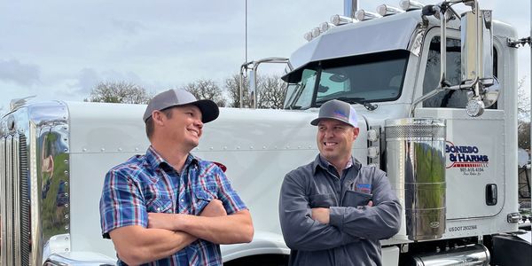 Two brothers-in-law laughing in front of truck