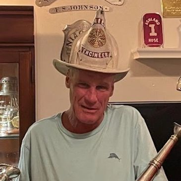 Man wearing a vintage firefighter helmet indoors.