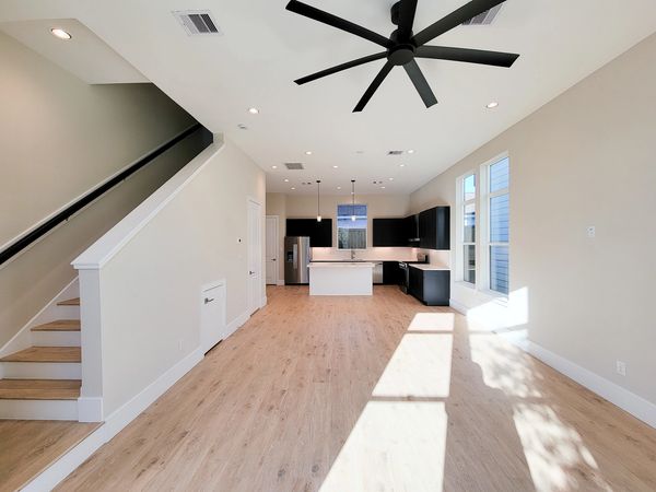 Vacant living space with a staircase, pale walls, and light wood floors
