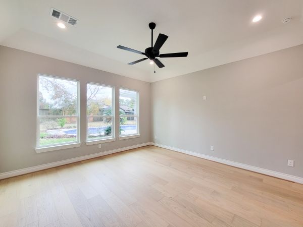 Vacant bedroom with light walls, a large window, and wood flooring