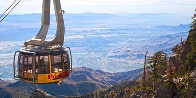 A cable car ascends over a mountainous landscape with a city below.