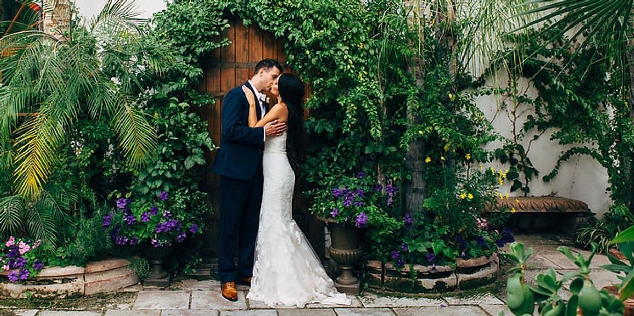 bride and groom kissing in front of oak door surrounded by vines
