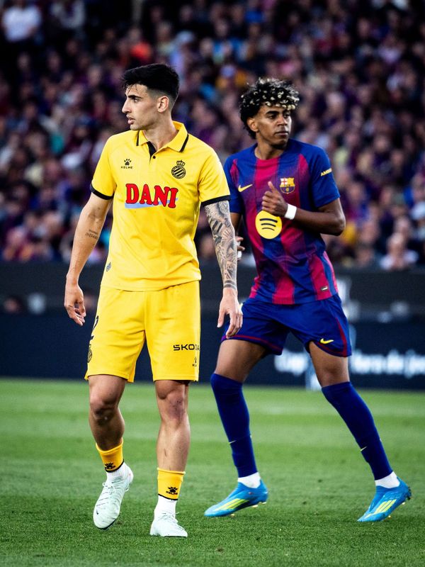 Two soccer players from opposing teams on the field during a match.