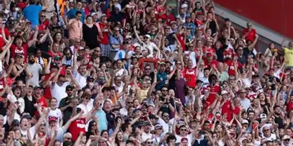 A large crowd of enthusiastic sports fans cheering in a stadium.