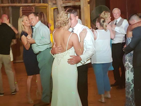 Couples dancing closely in a warmly lit rustic venue.