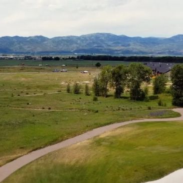 Golf course with mountain backdrop under cloudy sky.