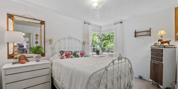 Cozy white bedroom with vintage bed and floral pillows.