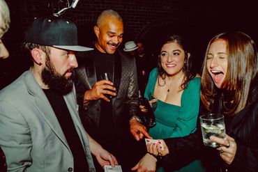 A group of friends enjoying a card trick at a lively party.