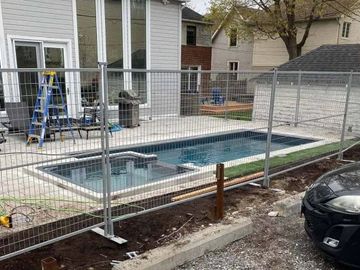 Backyard pool under construction with a temporary fence and tools around.