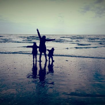 A mum and her two kids playing on a beach. Lowlight. Photo by JDMurphy.