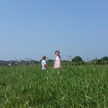 Two children playing in a field of long grass on a sunny summer day. Photo by JDMurphy.