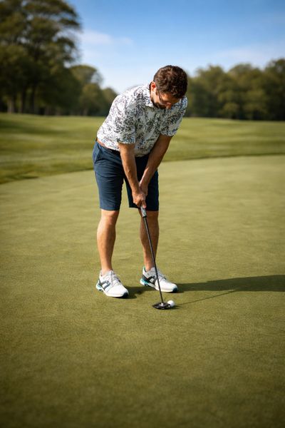 Man playing golf, preparing to putt on a green.