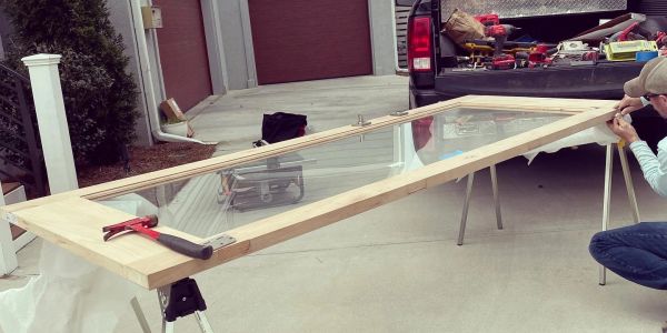 Person working on assembling a window frame outdoors.