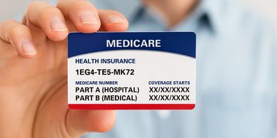 Hand holding a Medicare health insurance card with coverage details.