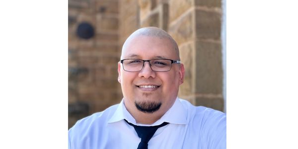 Smiling man with glasses and a goatee in a white shirt and tie.