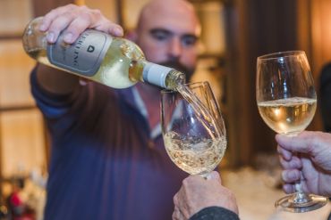 Person pouring white wine into a glass.