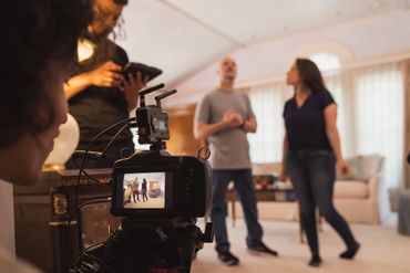 Camera filming two people interacting in a living room.