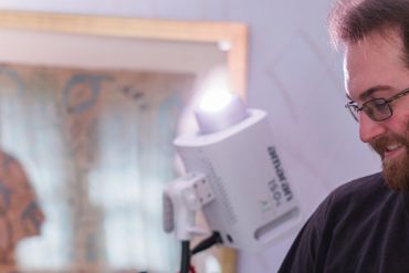 Bearded man holding a clapperboard on a film set.