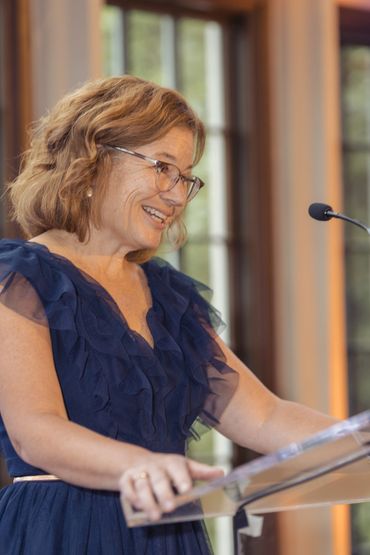 Woman in blue dress speaking at a podium with a microphone.