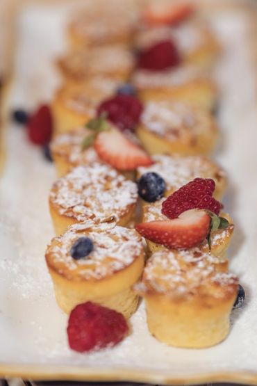 Mini almond cakes topped with powdered sugar and fresh berries.