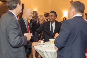 Four men in suits enjoying a conversation at a formal event.