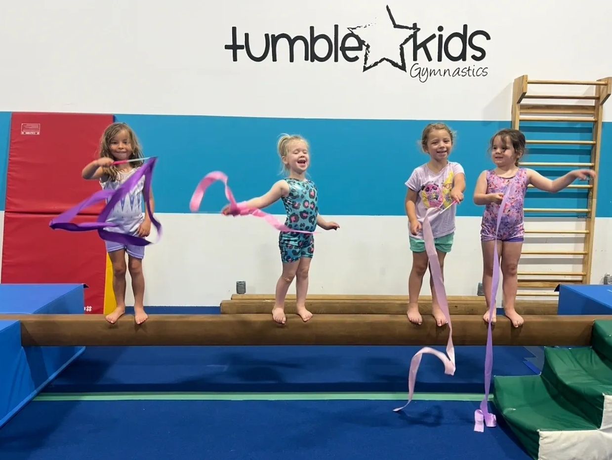 Group of children on beam with ribbons