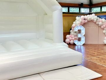 White Bouncy Castle with pink and white balloon sailboard display with light up number in esher