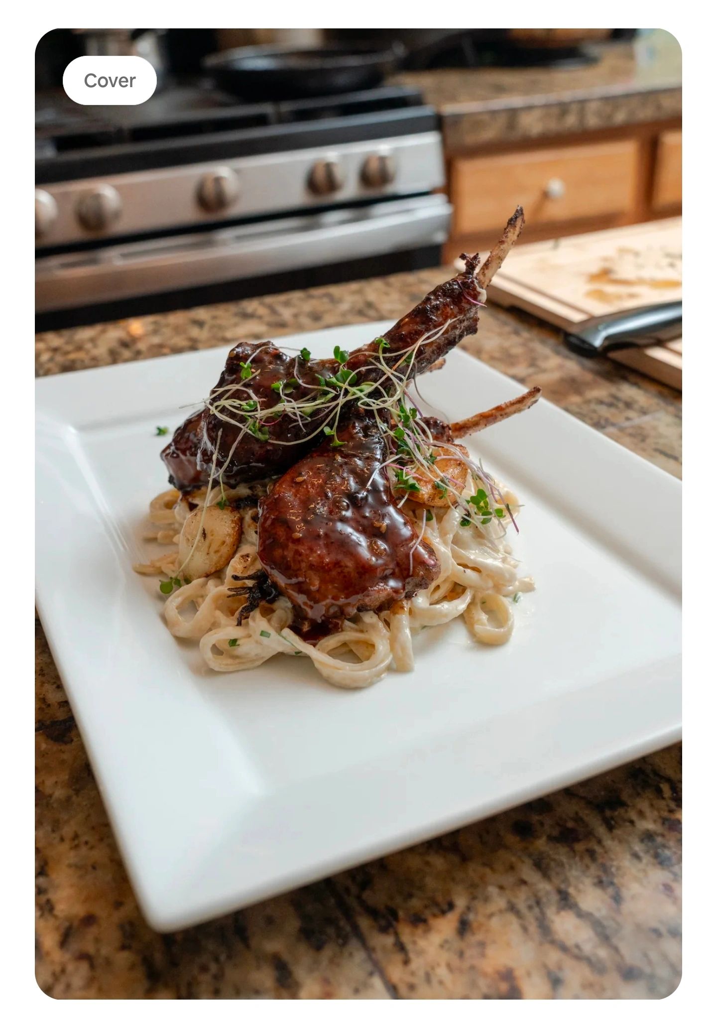 Grilled lamb chops on creamy pasta garnished with microgreens on a white plate.