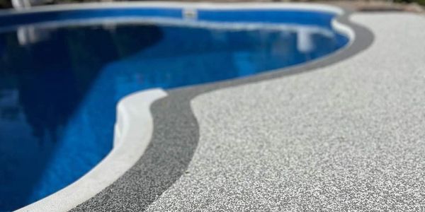 Curved pool edge with textured white and gray deck surface.