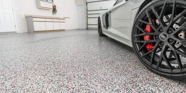 Sleek white Audi sports car parked on a polished speckled garage floor.