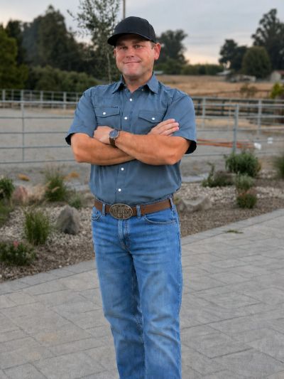 Photo of John La Bare standing by a horse riding arena.