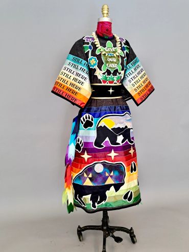 Colorful indigenous-themed dress with symbolic imagery and text.