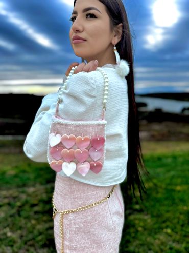 Woman with a pink heart-decorated bag outdoors.