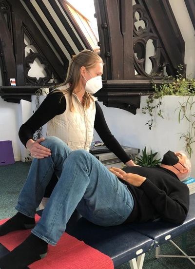 Client laying on teaching table. Natalie touching client's knee and shoulder