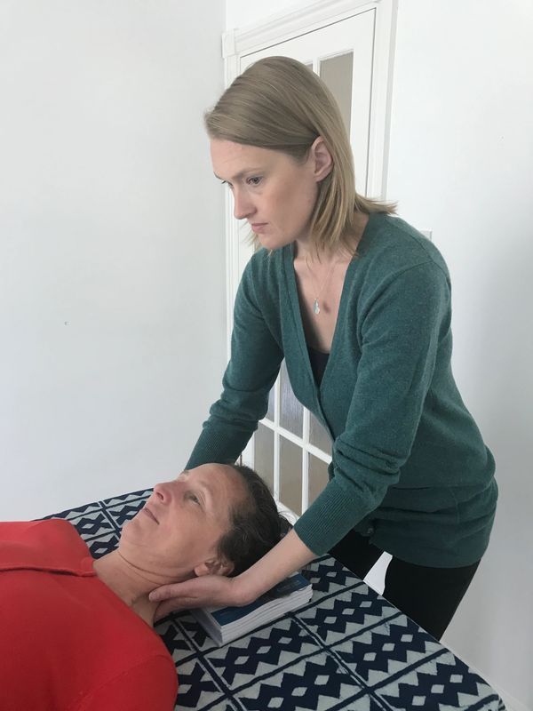 Client laying on table. Natalie touching back of client's neck and head.