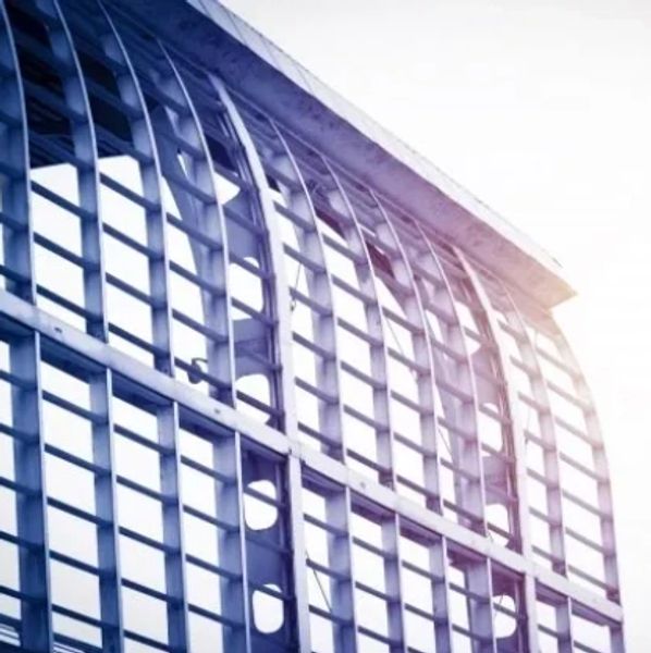 Modern glass building facade with metal framework and sunlight.